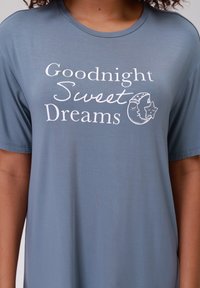 Maglietta blu a maniche corte con la scritta "Buonanotte, Sogni d'Oro" accompagnata da una grafica di una luna e di una stella in bianco. Tessuto morbido e liscio.