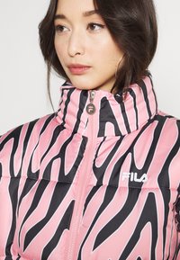 Giubbotto imbottito con colletto alto, caratterizzato da un motivo a strisce zebrate in rosa e nero, chiusura frontale con zip e un logo bianco sul petto.