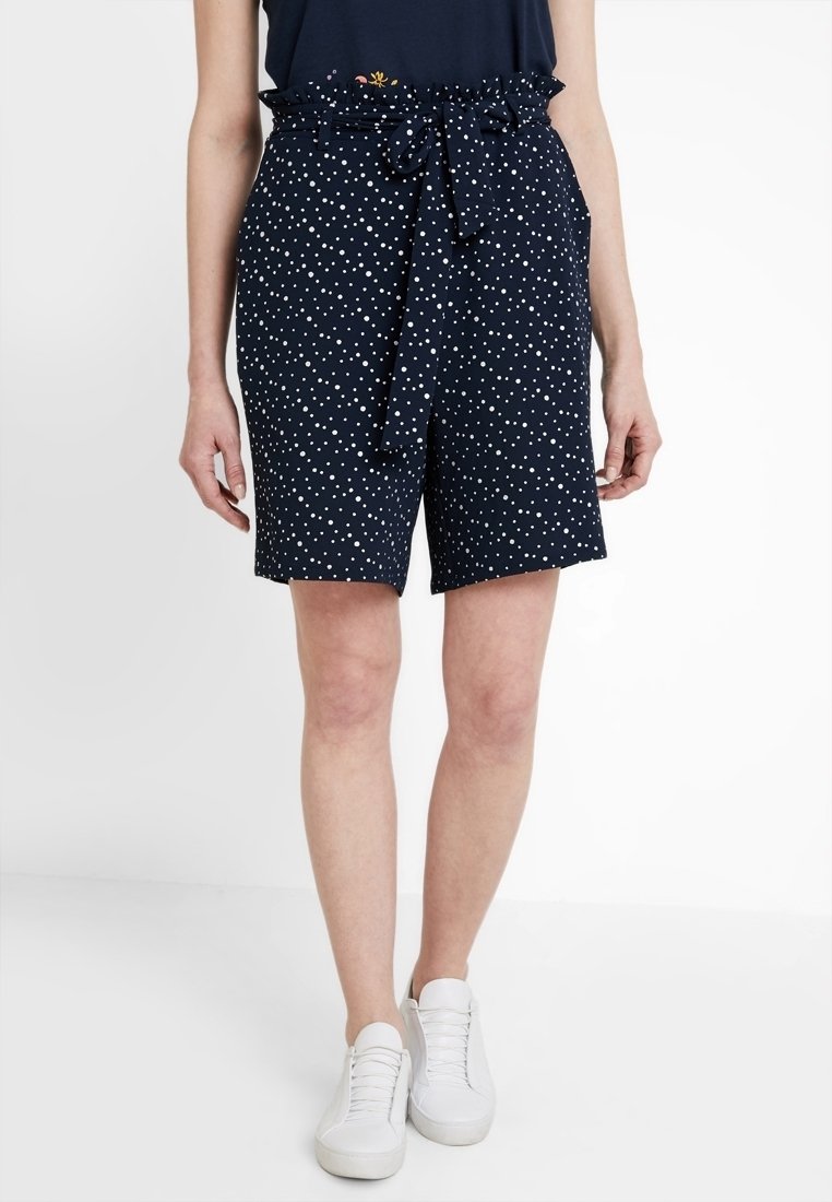 Granatowe szorty w białe grochy, z wysokim stanem, marszczoną elastyczną talią i paskiem wiązanym. Wykonane z lekkiego materiału.
