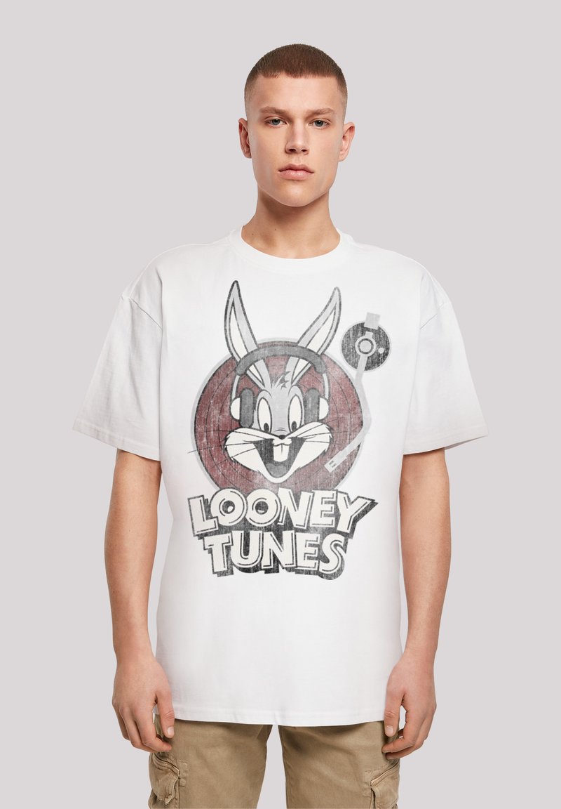 Bílý bavlněný tričko s velkým grafickým motivem Bugse Bunnyho s sluchátky a textem "LOONEY TUNES" pod ním, krátké rukávy a uvolněný střih.