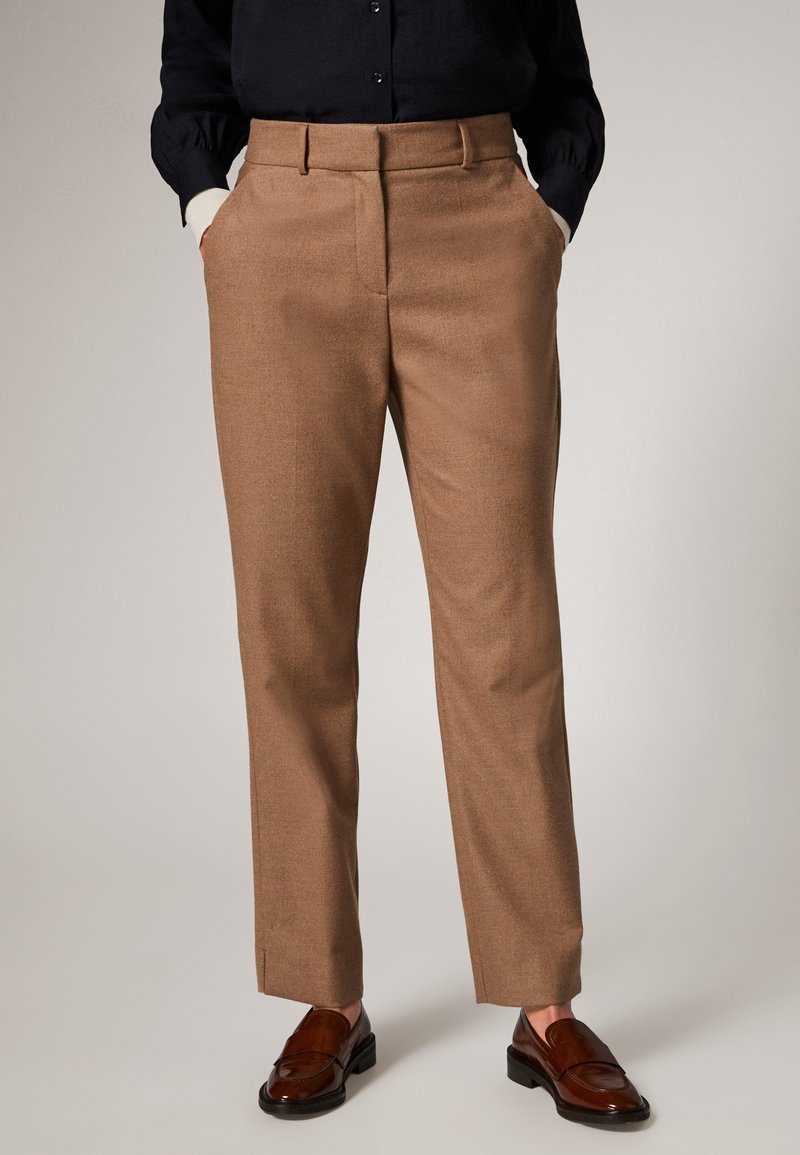 Tan kleurige broek van gestructureerde stof, met een recht model, zijzakken en een zachte waistband. Draagt het met donkere loafers.