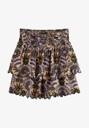 Jasnoniebieska bluzka z długim rękawem w połączeniu z warstwową, wzorzystą spódnicą z motywem kwiatowym w odcieniach fioletu i zieleni, uzupełniona czarnymi botkami.