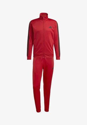 Tuta da ginnastica rossa realizzata in materiale lucido, dotata di giacca con zip e colletto alto e strisce nere sui lati, abbinata a pantaloni aderenti.