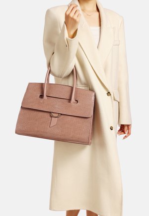 Borsa rosa con motivo coccodrillo, dalla forma strutturata, dotata di due manici e chiusura a pattina, tenuta da una persona in un cappotto crema.