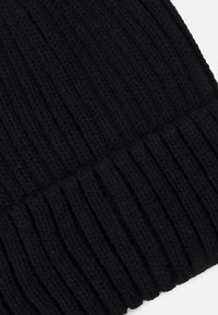 Sort strikket hue med ribbet tekstur og en afsluttet kant. Stoffet fremstår blødt og tykt for varme og komfort.