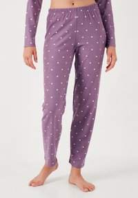 Violetit pyjamat, jotka ovat pehmeää kangasta ja joissa on valkoisia pilkkuja. Joustava vyötärö, slim fit -malli ja nilkkapituisuus.