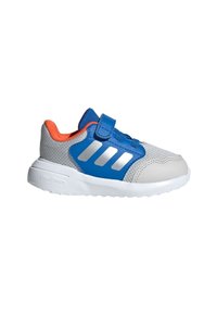 Szaro-niebieski but sportowy z cholewką z siateczki, paskiem na rzep, trzema srebrnymi paskami i białą podeszwą. Pomarańczowe akcenty na kołnierzu.