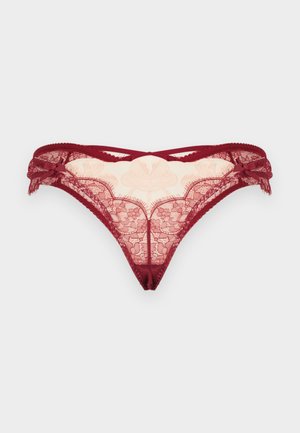 Červené čipkované nohavičky so kvetinovou výšivkou, priehľadnou látkou a malými dekoratívnymi mašličkami na bokoch, zobrazené na jednofarebnom pozadí.