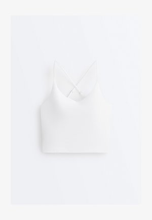 Fehér, rövidített fazonú trikó vékony, állítható keresztpántokkal és V-nyakkivágással, egyszerű fehér háttéren bemutatva.