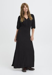 Rochie maxi neagră cu decolteu în V, mâneci bufante �și talie ajustată. Confecționată dintr-un material moale, cu o textură netedă și o siluetă fluidă.