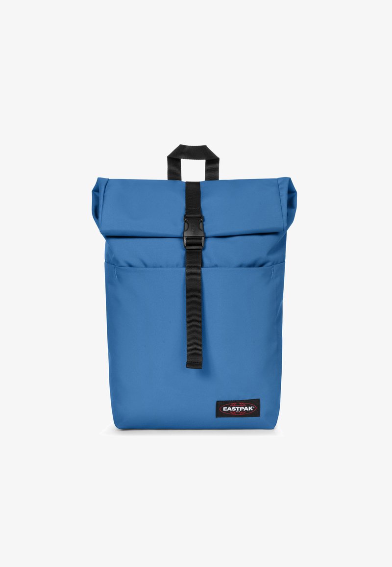 Blå rulltoppryggsäck gjord av slitstarkt tyg, med en framknäppning, handtag upptill och Eastpak-logotyp längst ner.