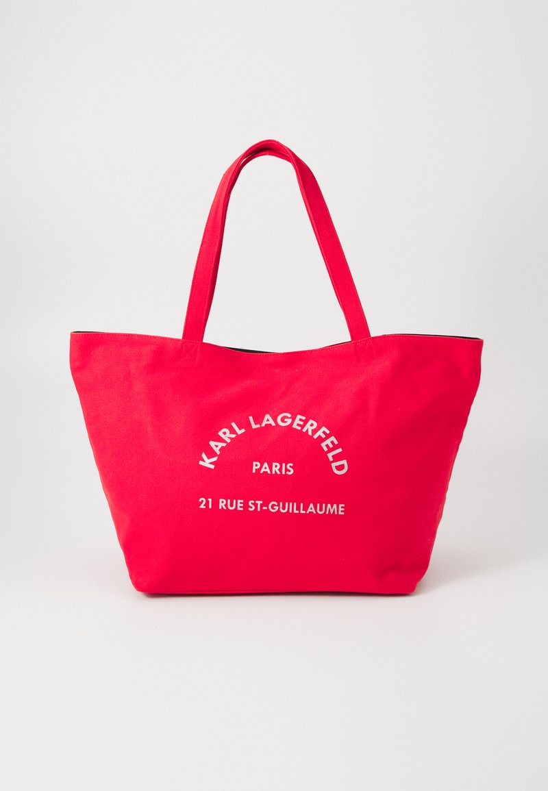 Sac fourre-tout en toile rouge avec deux poignées, arborant un texte imprimé en blanc : "KARL LAGERFELD PARIS 21 RUE ST-GUILLAUME."