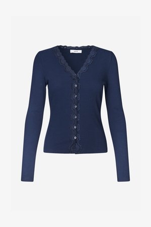 Κάρντιγκαν σε ναυτικό μπλε χρώμα, κατασκευασμένο από ριμπ ύφασμα με διακοσμητική δαντέλα σε σχέδιο κυματοειδούς άκρης και έξι διακοσμητικά κουμπιά μπροστά. Φαρδιές μακριές μανσέτες.