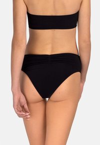 Czarny bikini bandeau z dopasowanymi wysokimi majtkami. Materiał wydaje się gładki, z subtelnymi marszczeniami w pasie.