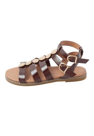 Brązowy skórzany płaski sandał z wieloma paskami, złotymi ozdobnymi guzikami oraz podwójnymi regulowanymi klamrami na jasnobeżowej podeszwie.