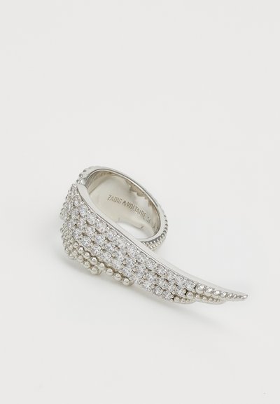 Silberring mit wellenförmigem Design, ausgestattet mit Reihen von klaren Kristallen, kleinen Perlen am Rand und einem eingravierten Markennamen im Inneren.