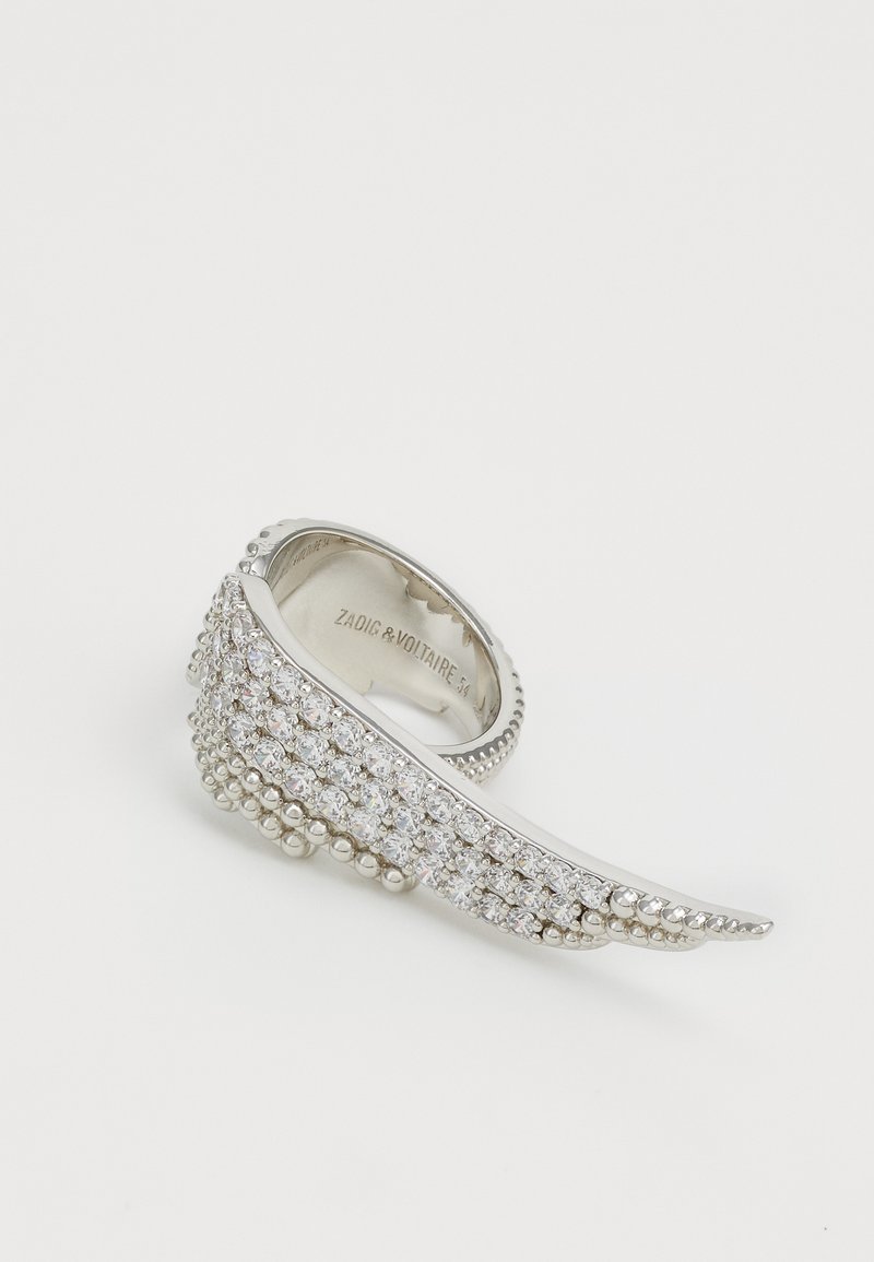 Silver ring with a wavy design, featuring rows of clear crystals, small beads along the edge, and an engraved brand name inside.