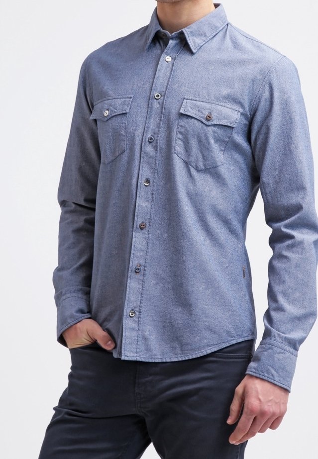 Dark blue button-up shirt with a subtle texture, featuring two chest pockets, metal buttons, and a pointed collar. Long sleeves, straight hem.