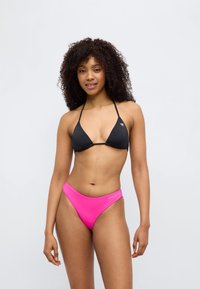 Μαύρο τριγωνικό μπικίνι τοπ με λεπτές τιράντες και ροζ σλιπ ψηλόμεσο με λεπτομέρεια λογότυπου. Λείο, ελαστικό ύφασμα.