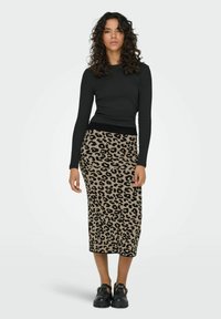 Haut à manches longues noir associé à une jupe léopard de mi-longueur beige et noire. Le mannequin porte des chaussures noires imposantes.
