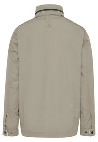 Light beige jacket with a high collar, zip closure, and snap-button cuffs. Features subtle stitching and a contrasting striped detail.