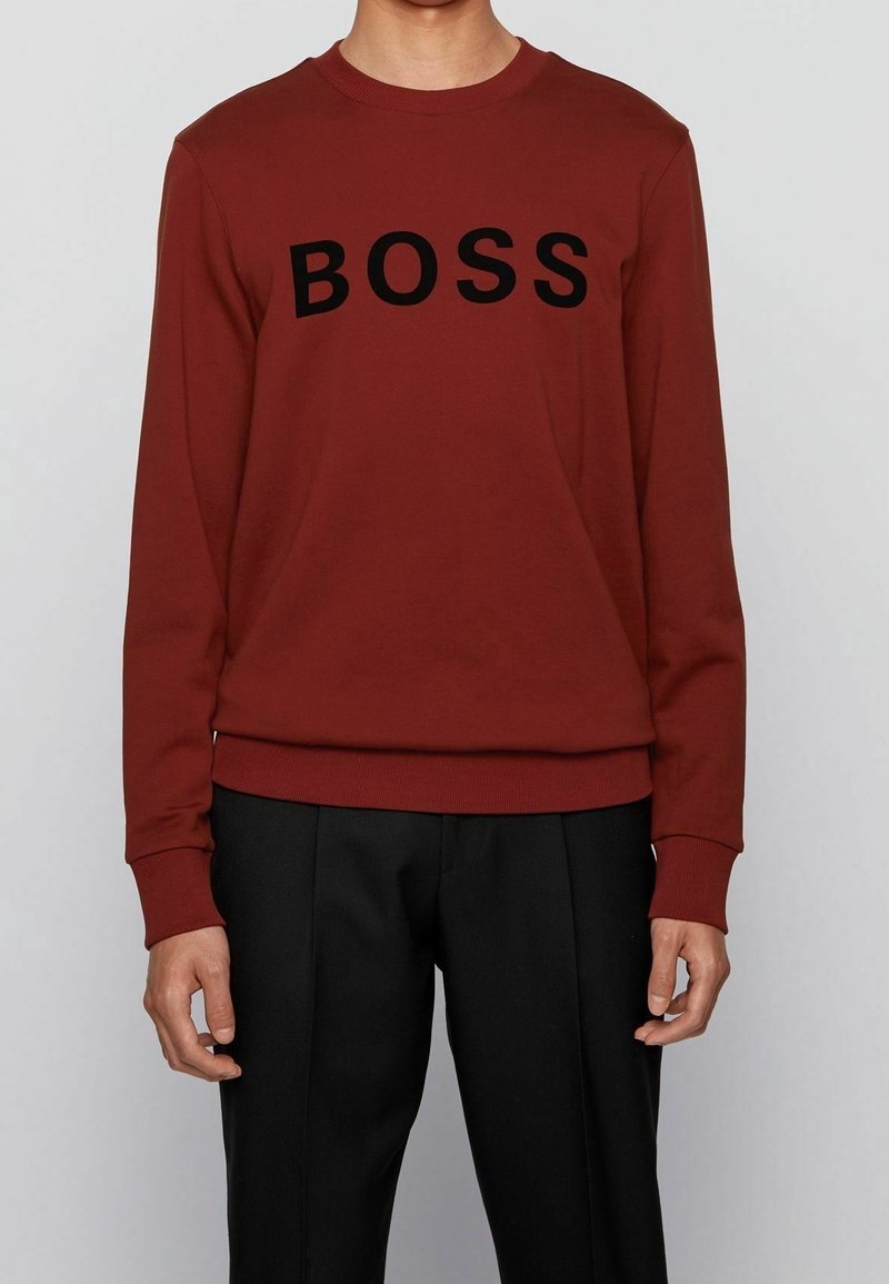 Sweatshirt bordeaux à manches longues, col rond côtelé et inscription noire « BOSS » sur la poitrine. Tissu lisse, coupe décontractée.