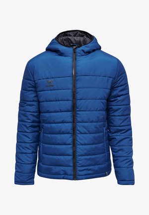 Veste matelassée bleue avec capuche, présentant des coutures horizontales, une fermeture éclair à l'avant et un logo sur la poitrine. Texture lisse, design léger.