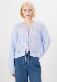 Světle modrý pletený kardigan s otevřeným předním dílem, dlouhými rukávy a vázáním na uzel. Má volný střih a strukturovaný úplet.