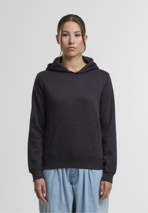 Schwarzer Hoodie aus weichem Material mit Fronttasche, Kordelzugkapuze und gerippten Bündchen. Dazu werden hellblaue Weite Leg-Hosen getragen.