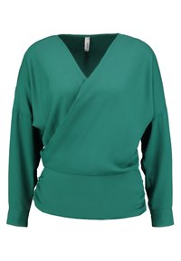 Grüne Bluse mit langen Ärmeln, V-Ausschnitt und überlappendem Vorderteil, mit gerafften Seiten. Sie hat einen breiten, bandartigen Saum und eine glatte Stoffstruktur.