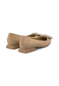 Ballerines en daim couleur tan avec un nœud décoratif en strass. Semelle basse et angulaire distinctive. Texture lisse, design fermé.