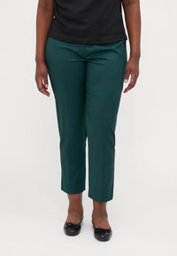 Zelené, středně vysoké kalhoty s slim fit a zúženými nohavicemi, vyrobené z hladkého materiálu. Doplněné o černé baleríny.