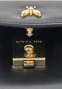 Interiøret i den svarte skinnvesken har et gullmetallisk lås med et dekorativt bieemblem, preget med "PATRIZIA PEPE."