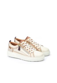 Zapatillas blancas y beige con una suela texturizada, con detalles metálicos en dorado y púrpura, cordones y un detalle de cremallera lateral.