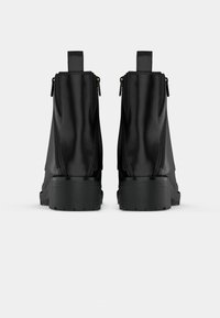 Mustad nahast pahkluusaapad siledaga, millel on kahepoolne tõmblukk, tugev kummist tald ja taga tõmblõng.