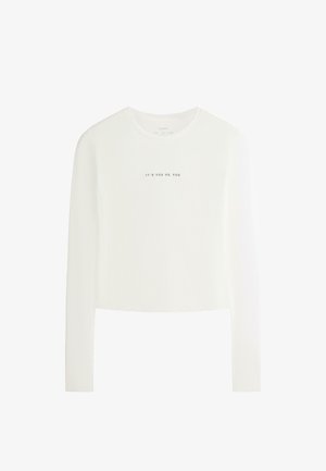 Top scurt alb cu mâneci lungi, gât rotund și text negru "IT'S YOU VS. YOU" centrat pe piept.