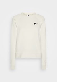 Svetle béžová mikina s kulatým výstřihem, raglánovými rukávy a černým logem Nike na hrudi. Vyrobena z měkké látky s žebrovanými manžetami.