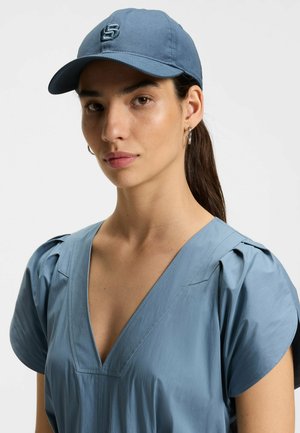 Blue cap made of cotton, featuring a rounded visor and embroidered logo on the front. The cap has a smooth texture and adjustable back.