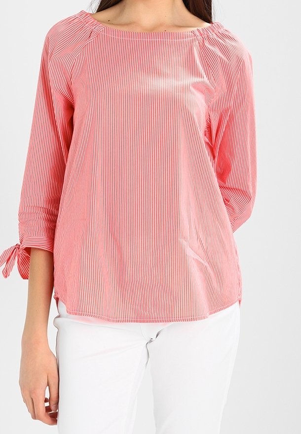 Blouse rayée rouge et blanche avec un décolleté bateau, des manches trois-quarts et des détails de lien au niveau des poignets. Tissu léger avec une texture douce.
