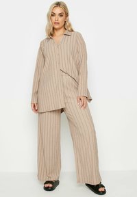 Completo coordinato a righe beige composto da una camicia a maniche lunghe con bottoni e pantaloni a gamba larga, realizzato in tessuto testurizzato con una vestibilità rilassata.