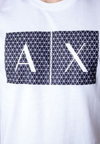 White cotton t-shirt featuring a black geometric pattern with the letters "A" and "X" inside two rectangular shapes.
