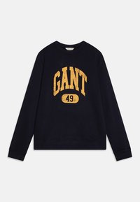 Námornícky modrý sveter vyrobený z bavlny s rebrovaným okrúhlym výstrihom, s veľkým, opotrebovaným žltým grafickým znakom "GANT" a číslom "49."
