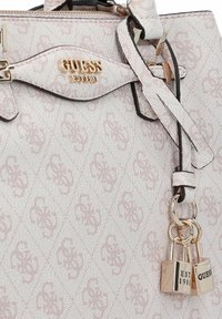 Sac à main texturé rose avec un logo en métal doré, deux cadenas et un design structuré. Présente des bordures noires et une sangle lisse.