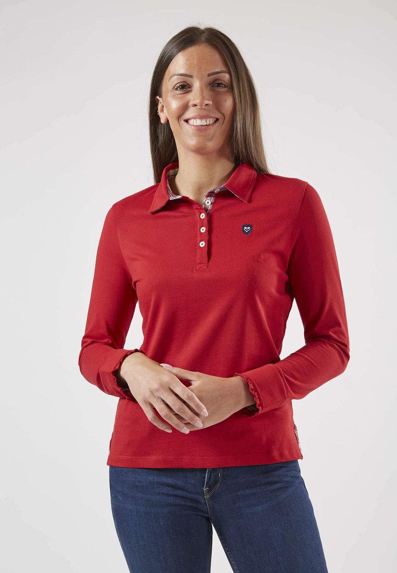 Polo-shirt rouge à manches longues avec un col, une patte de boutonnage et un col intérieur à motifs. Présente des poignets de manches à volants et un petit logo.