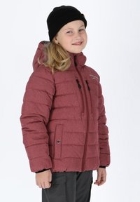 Giacca imbottita rossa con cappuccio, due tasche con zip e finitura testurizzata, indossata con un berretto a maglia nero. Presenta una zip frontale completa.