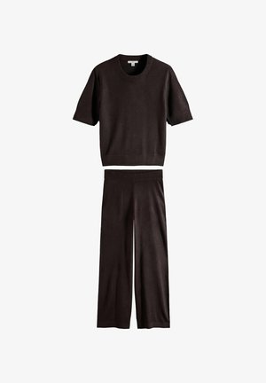 Schwarzes Kurzarm-Stricktop und passende weit geschnittene Hosen, flach auf weißem Hintergrund ausgelegt.