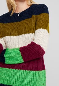 Suéter de punto grueso con rayas horizontales en navy, oliva, crema, burdeos y verde; escote redondo, material texturizado, ajuste holgado.