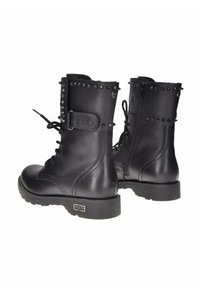 Stivali da combattimento in pelle nera con dettagli borchiati, chiusura lacci frontale, zip laterale e suola robusta per una migliore aderenza.