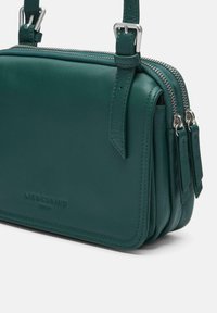 Torba na ramię z turkusowej skóry o prostokątnym kształcie, z podwójnym zamkiem błyskawicznym, regulowanym paskiem i wytłoczonym logo marki na przodzie.