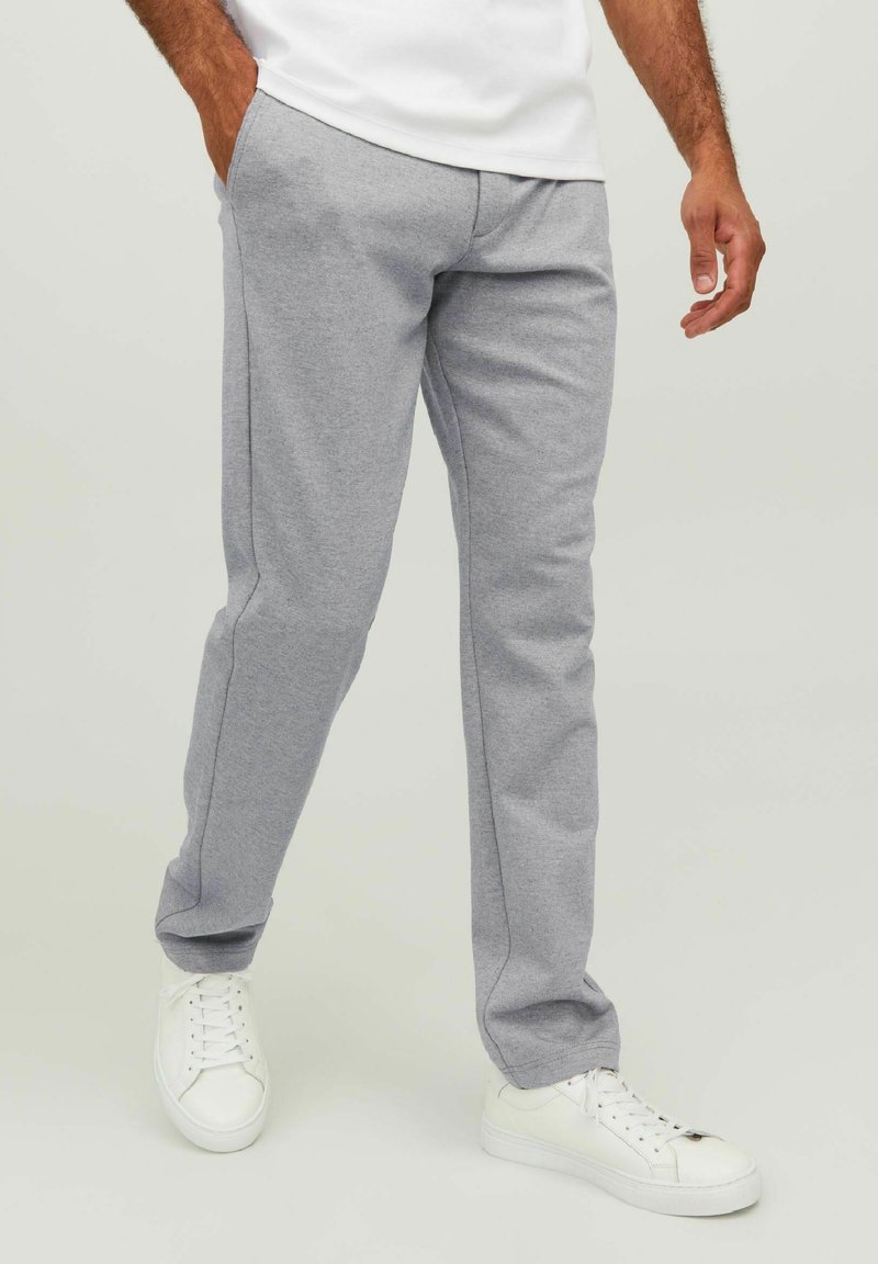 Pantaloni sportivi grigi realizzati in morbido tessuto misto cotone, dotati di tasche laterali, design a gamba dritta e sneakers bianche.